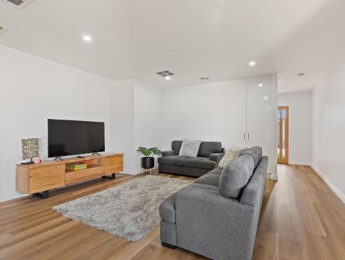 a living room with two couches and a flat screen tv at Rosella Retreat in Yarrawonga