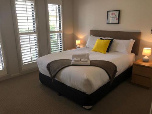 a bedroom with a large bed with two windows at Cypress 39 A in Mulwala