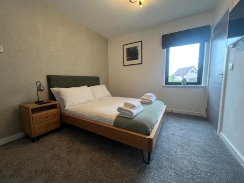 a bedroom with a bed with two towels on it at The Peaks Three Bed Apartment in Aviemore