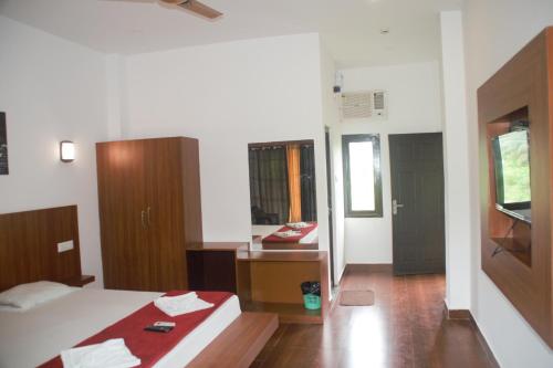 a bedroom with a bed and a desk and a mirror at Hotel Exotica Squares in Neil Island
