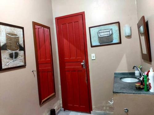 ein Bad mit einer roten Tür und einem Waschbecken in der Unterkunft Casa em Soure Ilha de Marajó. in Soure
