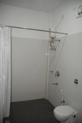a white bathroom with a toilet and a shower at Hotel Exotica Squares in Neil Island