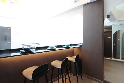 a kitchen with black counter tops and stools at ST Signature Bugis Beach in Singapore