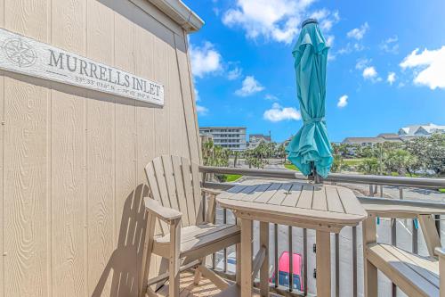 a table and chairs with an umbrella on a balcony at Cozy Condo, Beach Access, Dock, Pool, Sunsets in Myrtle Beach