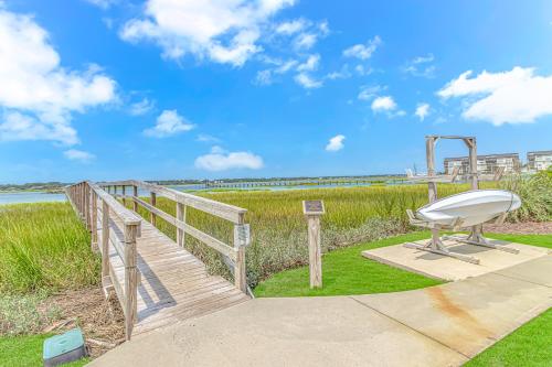 a wooden boardwalk leading to a beach with a bench at Cozy Condo, Beach Access, Dock, Pool, Sunsets in Myrtle Beach