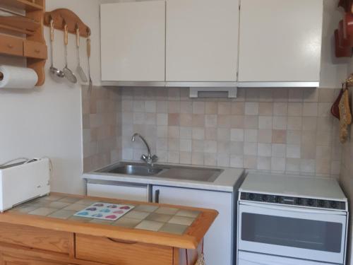 une cuisine avec des armoires blanches et un évier dans l'établissement Séjour cosy en studio à Serre Chevalier, 4 pers, balcon, au pied des pistes, navette gratuite - FR-1-762-28, à La Salle Les Alpes