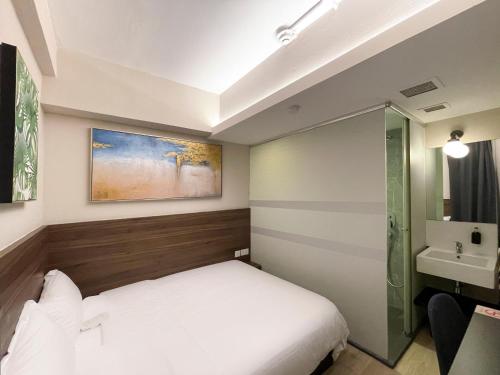 a small bedroom with a bed and a sink at ST Signature Bugis Beach in Singapore