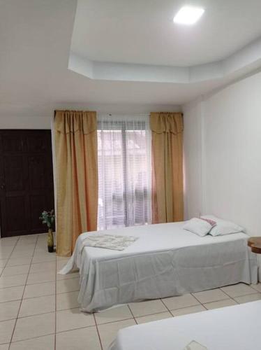 a white bedroom with a bed and a window at Paradise Celeste in Bijagua