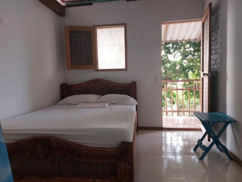 1 dormitorio con cama, ventana y silla en Hostal El Nido del Azulejo, en Barú