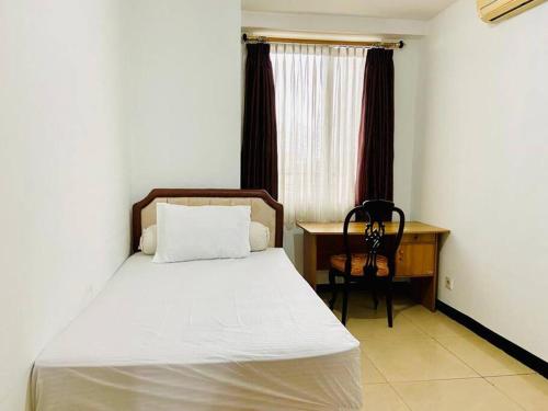 a bedroom with a bed and a desk and a window at Apartemen Paladian Kelapa Gading Syariah in Jakarta
