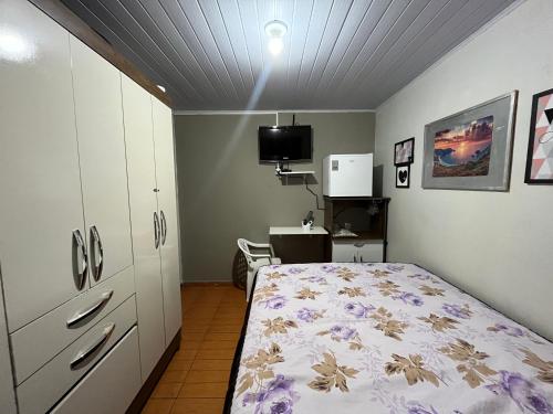 een slaapkamer met een bed, een bureau en een televisie bij Casa Recanto - Quarto simples in Rio Verde