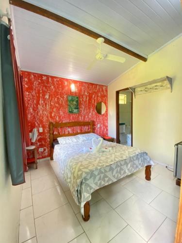 a bedroom with a bed and a red wall at Suítes Doce Lar in Paraty