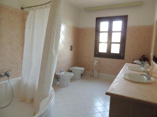 a bathroom with two sinks and a toilet and a window at Il Nuraghe in Uras
