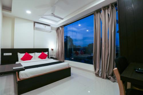 a bedroom with a bed and a large window at Capital O GN Suites in Bengaluru