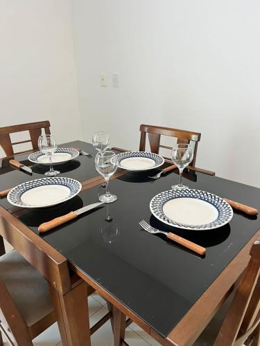 a table with chairs and plates and wine glasses at Luz do Sol Prainha - 3 Quartos in Arraial do Cabo