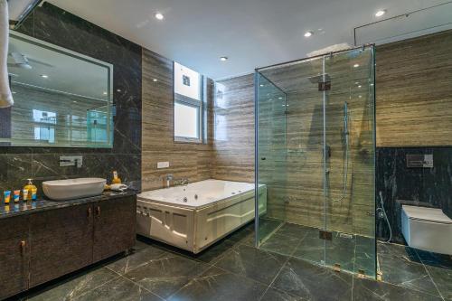 a bathroom with a tub and a sink and a shower at StayVista at Blanc Belle With outdoor pool in Sohna
