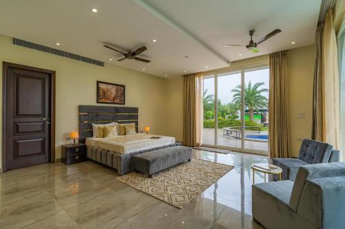 a bedroom with a bed and a couch and a window at StayVista at Blanc Belle With outdoor pool in Sohna