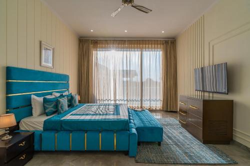 a bedroom with a blue bed and a flat screen tv at StayVista at Blanc Belle With outdoor pool in Sohna