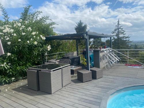 eine Terrasse mit einem Whirlpool und einem Sonnenschirm neben einem Pool in der Unterkunft Maison vue panoramique et accès SPA in La Réole