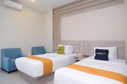 a hotel room with two beds and a blue chair at Urbanview Hotel Dedy Jaya Brebes in Brebes