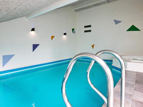 a swimming pool with blue water and triangles on the wall at 12 person holiday home in Bl vand in Blåvand