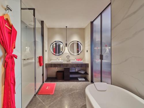 ein Bad mit einem WC, einem Waschbecken und Spiegeln in der Unterkunft Crowne Plaza Jiangmen Binjiang, an IHG Hotel in Jiangmen