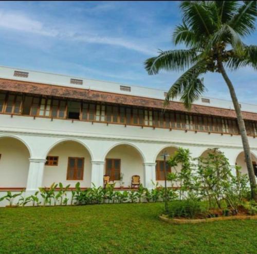 a building with a palm tree in front of it at Marari Beach Bungalow in Mararikulam