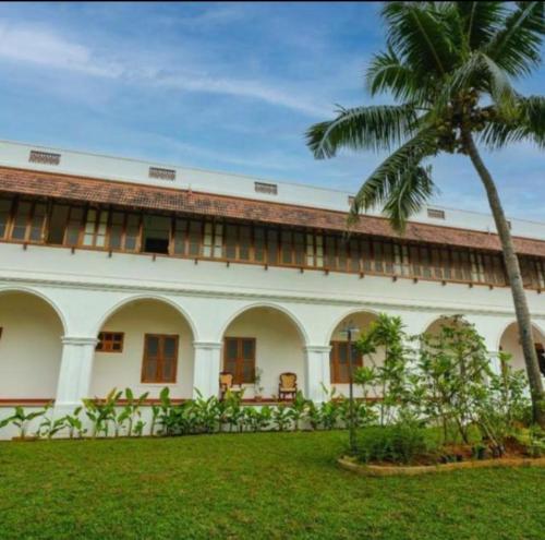 a building with a palm tree in front of it at Marari Beach Bungalow Resort Alleppey in Mararikulam
