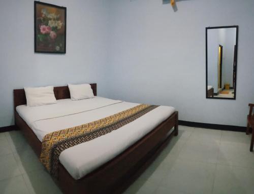 Ce lit se trouve dans un dortoir doté d'un miroir mural. dans l'établissement Hotel Ilhami Blitar, à Blitar