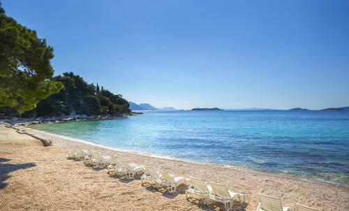 a sandy beach with chairs and the ocean at Aminess Grand Azur Hotel in Orebić