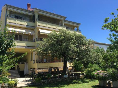a large yellow building with a tree in front of it at Apartments Kaja in Rab