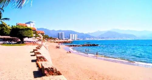 a beach with people walking on the sand and the water at Villa Marina in Puerto Vallarta