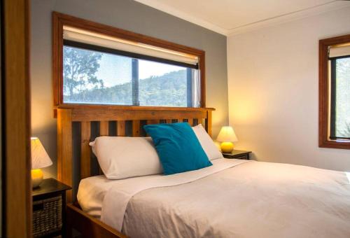 a bedroom with a bed with a blue pillow and a window at Bruny Island Escapes and Hotel Bruny in Alonnah