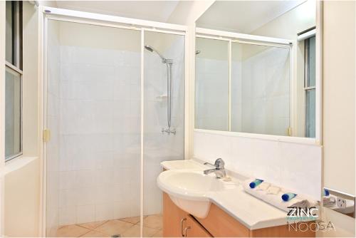 a white bathroom with a sink and a shower at Yaringa Apartment 1 - Moments from Noosa Main Beach in Noosa Heads