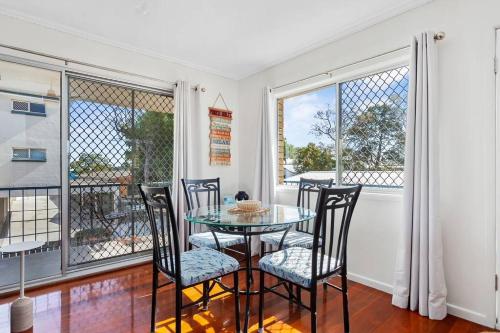 a dining room with a table and chairs and windows at Winston Waves in Bongaree