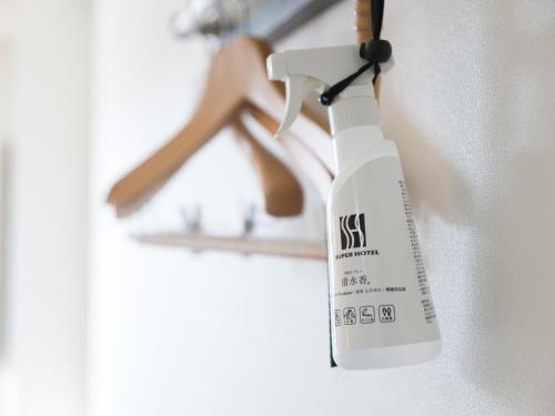 a white spray bottle hanging from a wall at Super Hotel Tokyo JR Tachikawa Kitaguchi in Tachikawa