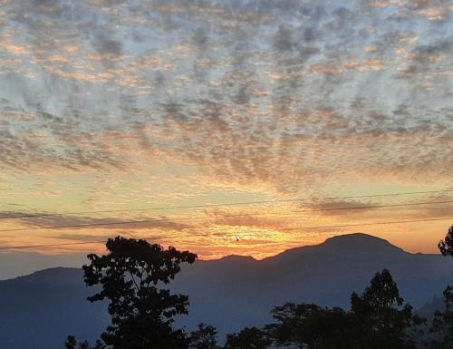 a sunset with mountains in the background and clouds at Khee Homestay in Kurseong