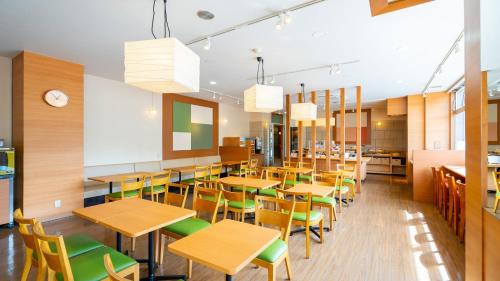 a classroom with wooden tables and green chairs at Vessel Inn Fukuyama Eki Kitaguchi in Fukuyama