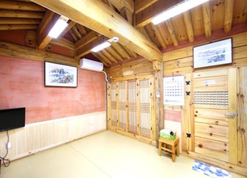 um quarto com paredes de madeira e uma televisão de ecrã plano em Danyang Hanok 단양한옥가대리 em Danyang