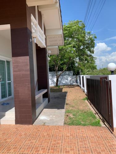 a building with a fence and a brick sidewalk at Baan Khun House in Nakhon Ratchasima