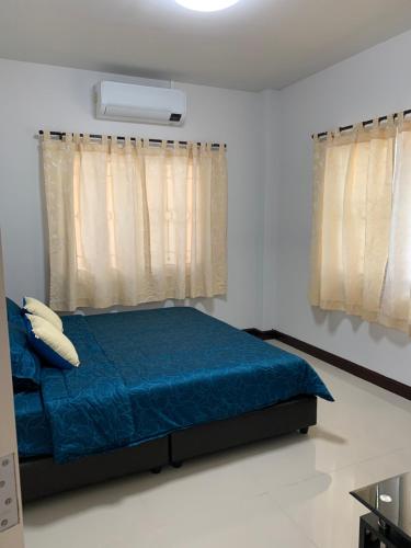 a bedroom with a bed with blue sheets and curtains at Baan Khun House in Nakhon Ratchasima