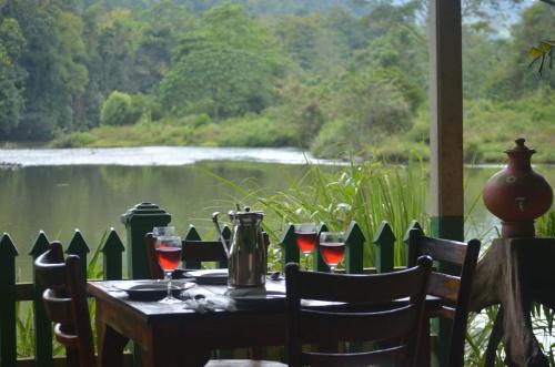una mesa con copas de vino y vistas al lago en Comfortable Eco Stays in Kitulgala with sightseeing & Adventure activities - Back Kate Resort, en Kitulgala