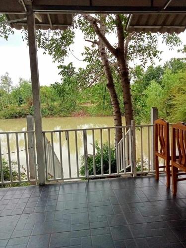 een veranda met 2 stoelen en uitzicht op een rivier bij โฮมสเตย์ แม่ปราณี 