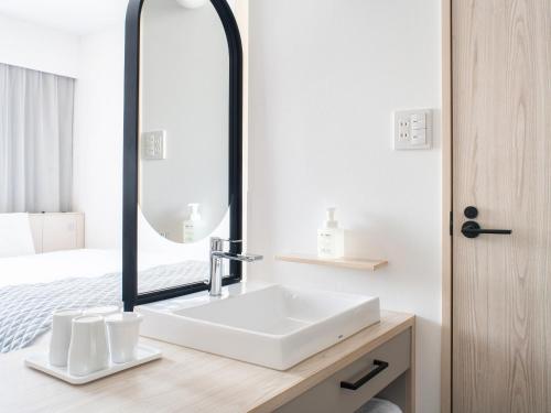a bathroom with a white sink and a mirror at Vessel Hotel Fukuyama in Fukuyama