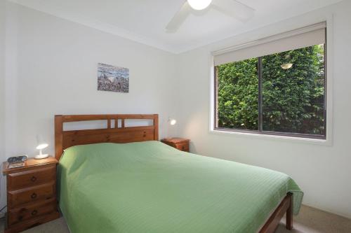 a bedroom with a green bed and a window at All Decked Out in Hawks Nest
