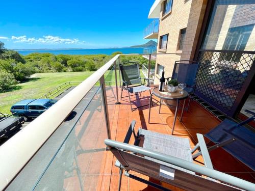 a balcony with chairs and a table on a house at 'Serenity Now' Shoal Bay Beach Front with All Linen, WiFi and Air Con in Nelson Bay