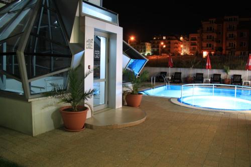 a building with a swimming pool at night at Guest House ASK in Primorsko