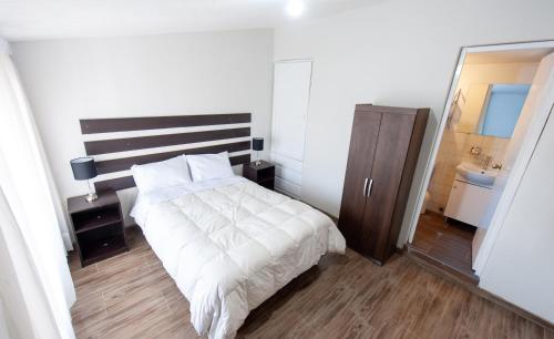 1 dormitorio con cama, lavabo y espejo en Moderno departamento Perumin en Arequipa
