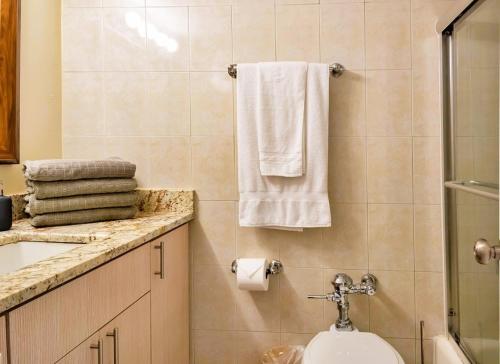 a bathroom with a sink and a toilet and towels at Steps to the Beach Christmas Vacation Pool in Hallandale Beach