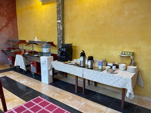a kitchen with two tables and a counter with food at Hotel Sugas in Sfântu-Gheorghe